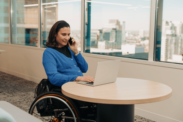 A professional taking a phone call while working on a laptop.